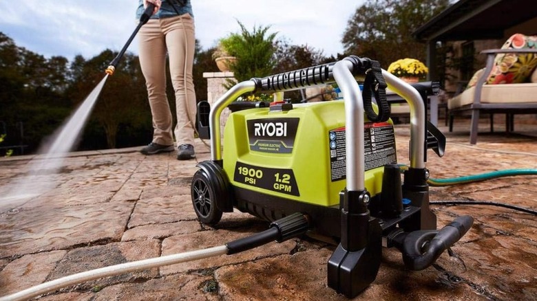 woman using Ryobi RY1419MT Pressure Washer on stone