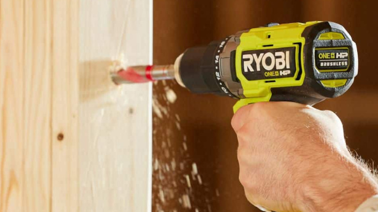 A person using a Ryobi drill on wood.