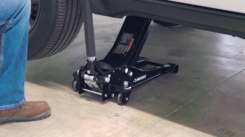Person using Husky car jack to hold up a vehicle