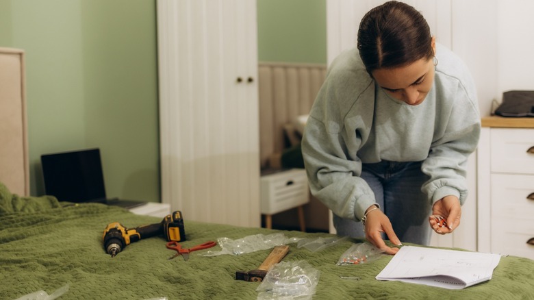 Woman reading instructions to assemble furniture