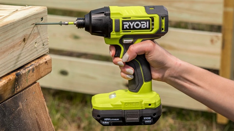 A person using a Ryobi impact driver on wood.