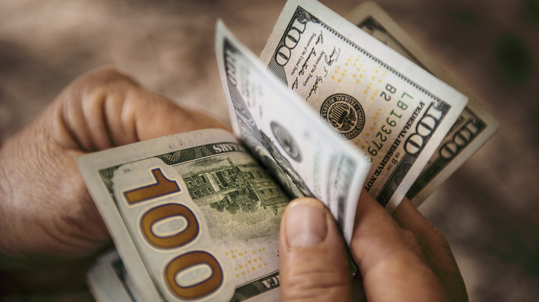 Person counting off $100 bills