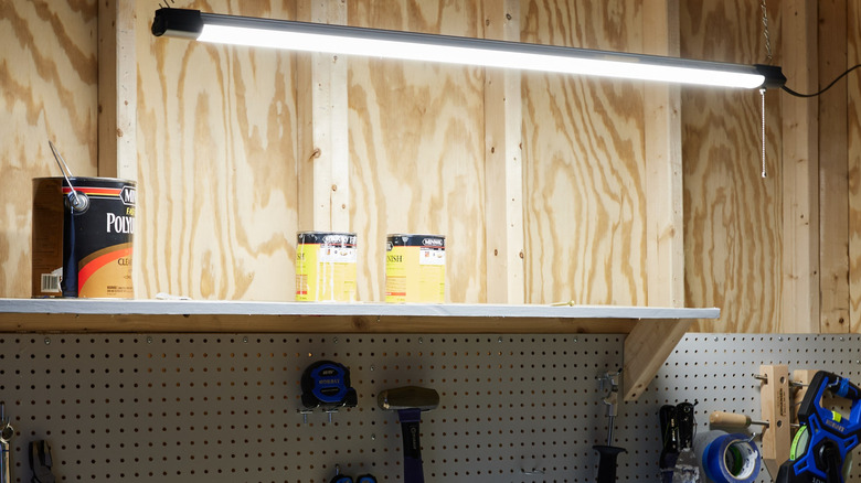 An Utilitech LED garage shop light hanging from the ceiling in a wooden building.