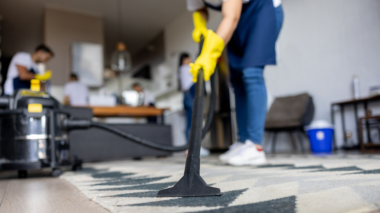 floor vac being used on carpet with cleaners in background