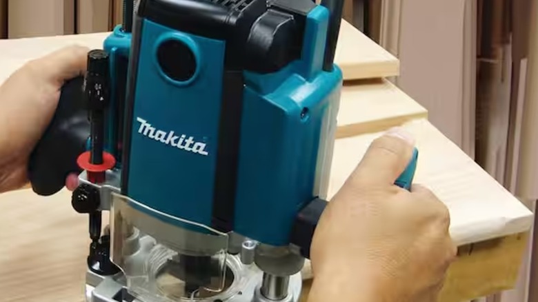 A person using the Makita corded plunge router.
