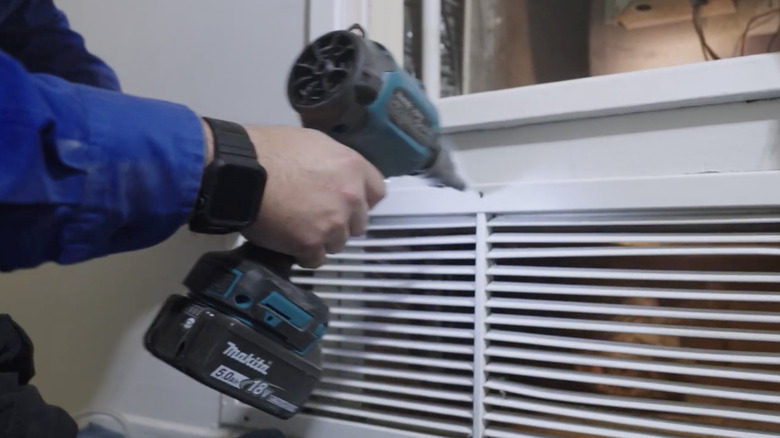 A man using a Makita blower to clean out an indoor vent