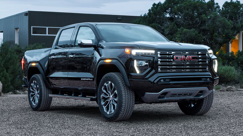 A black 2026 GMC Canyon parked in a suburban gravel parking lot