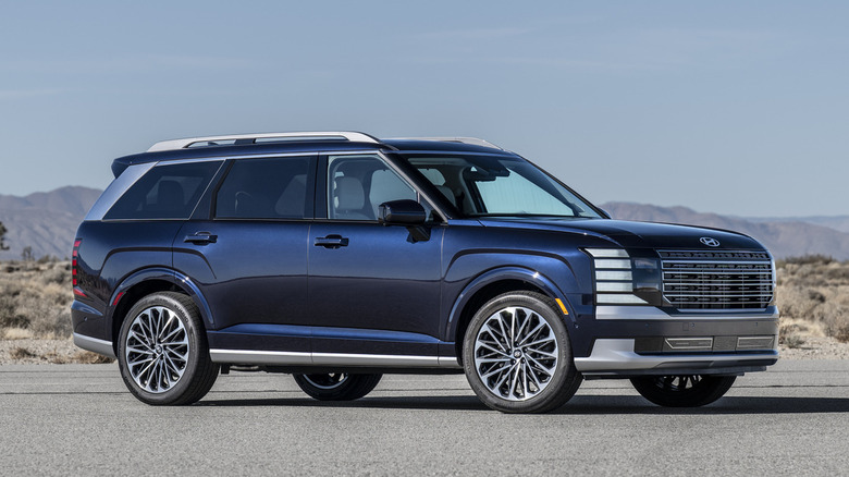 A blue 2026 Hyundai Palisade with striking silver accents parked on a road in the dessert