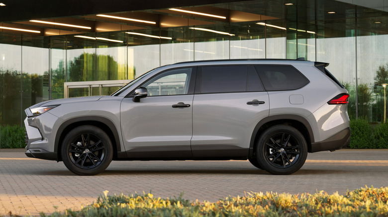 A gray 2026 Toyota Grand Highlander parked in front of a modern office building