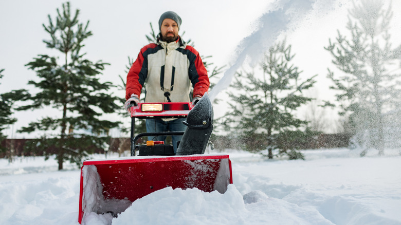 Person pushing a red snow blower