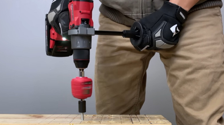 Worker using a Milwaukee M18 Fuel 1/2-inch hammer drill on a block of wood