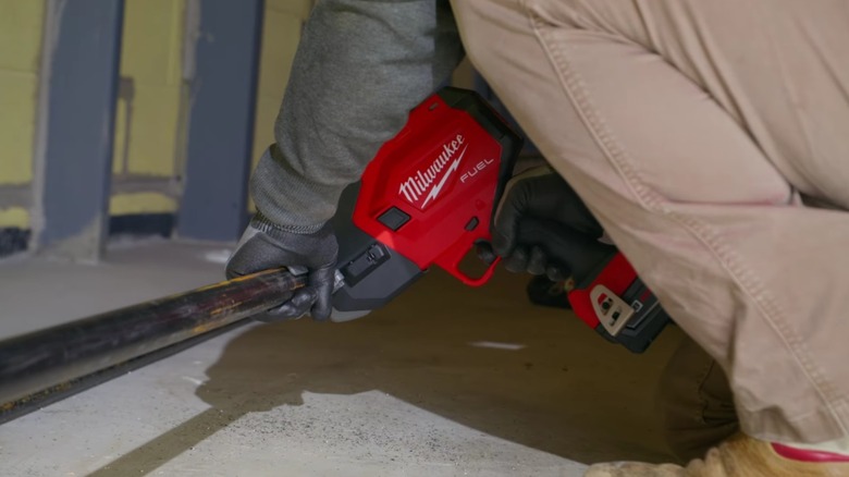 M18 FUEL™ ½-1 Steel Pipe Cutter cutting pipe near the ground.