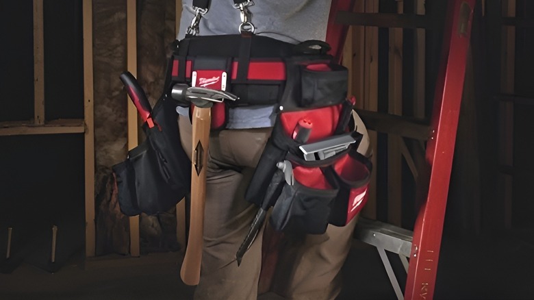 Man climbing ladder wit tool belt of Mlwaukee products