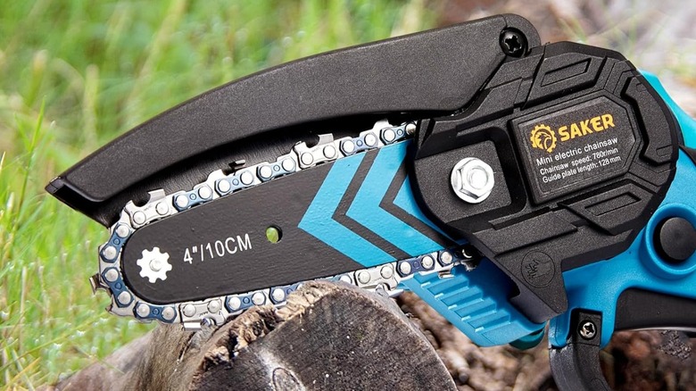 A Saker mini chainsaw resting on a log.