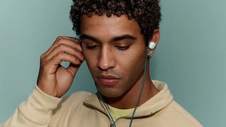 A person using wired Bose earbuds.