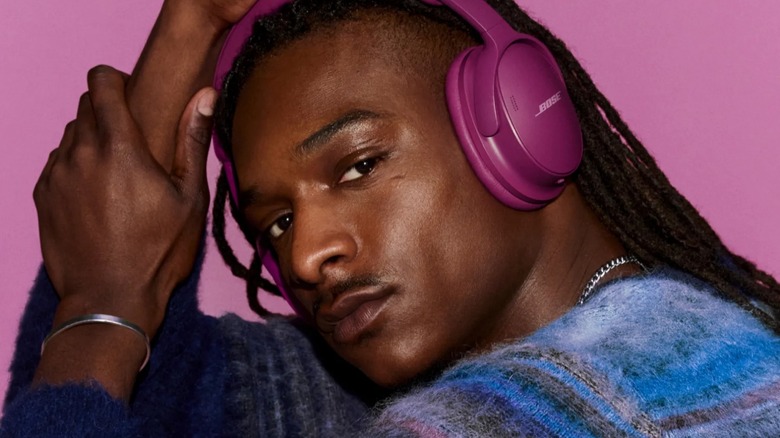 A person wearing pink Bose headphones.