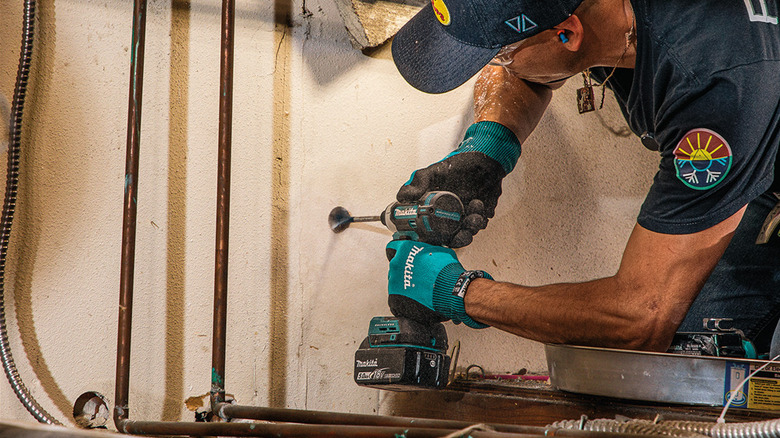 Repair person using the new Makita XDT21 impact driver on a dry wall.