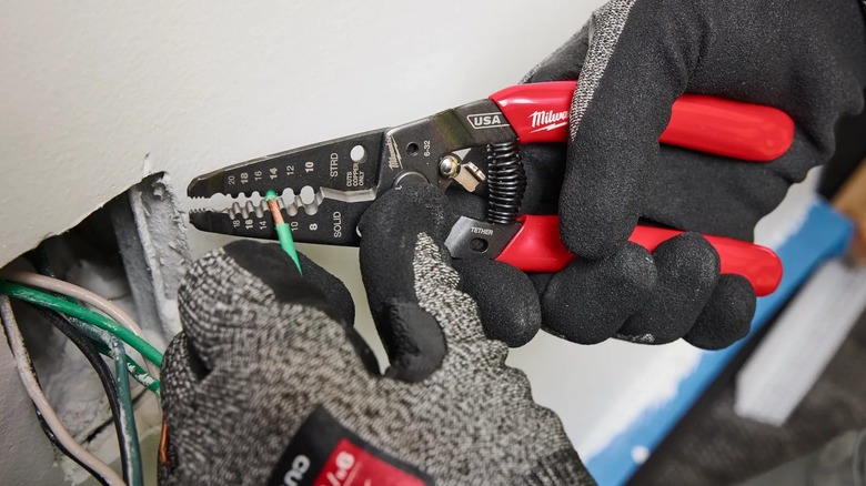 A person using Milwaukee pliers on wire.