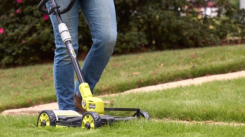Person using Ryobi 18V 3-in-1 tool to mow grass