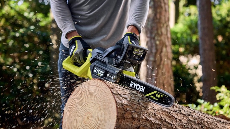 Person using Ryobi 18V chainsaw to cut a log
