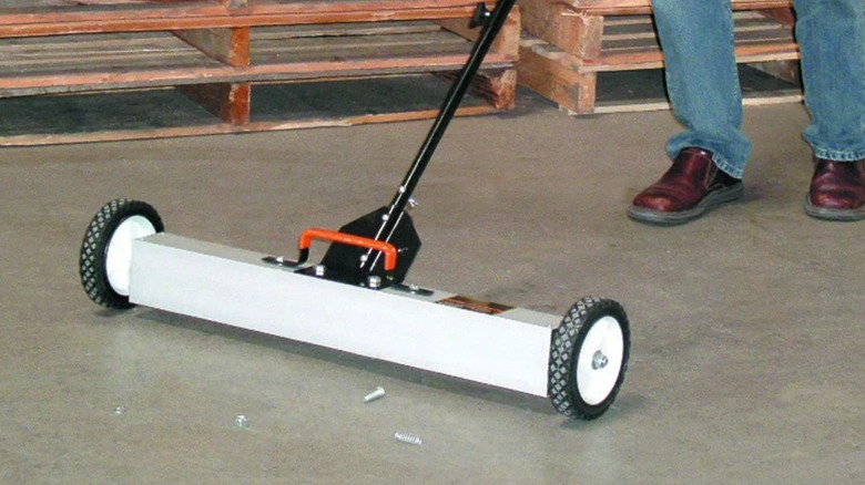 A person using a magnetic sweeper to pick up fasteners