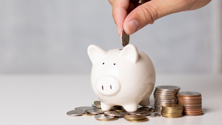 person inserting coin into piggy bank