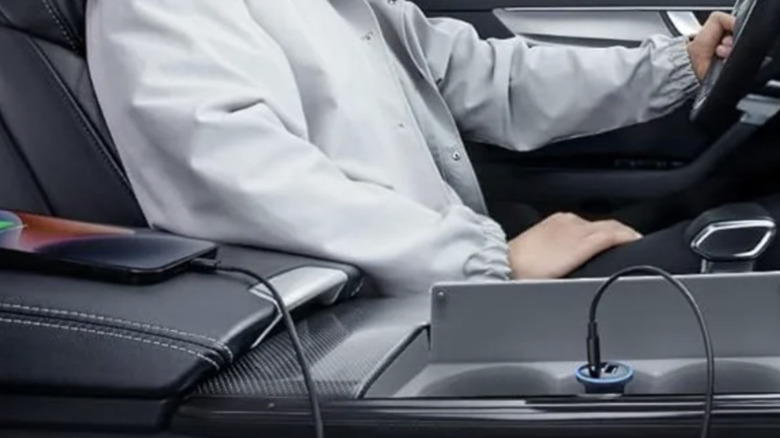 Close-up of a peson using an Anker car charger inside their vehicle to charge a smart phone