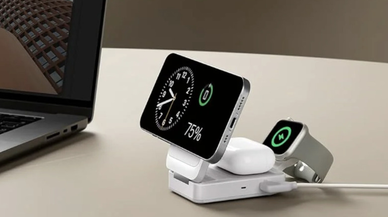 An white Anker wireless charging station set-up near a laptop and charging a phone, earbuds and watch