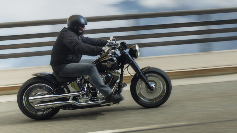 A person riding their Harley-Davidson down a road.