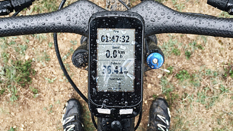 Close-up view of a bike computer between a bicycle's handlebars.