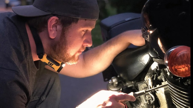 a person using a cat led neck light to work on a motorcycle