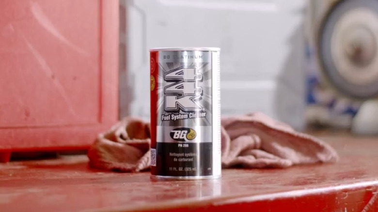 Can of fuel system cleaner on a red workbench with a red rag behind it