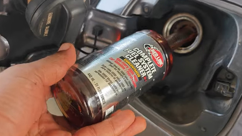Person pouring fuel system cleaner into gas tank