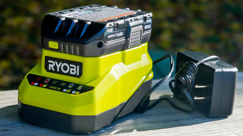 A Ryobi 18V battery sitting on an unplugged charger on a table outside