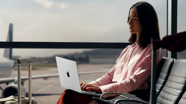 A person working with a MacBook Pro in an airport.