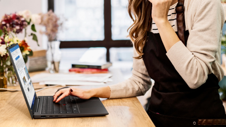 A person using a laptop on a kitchen counter.