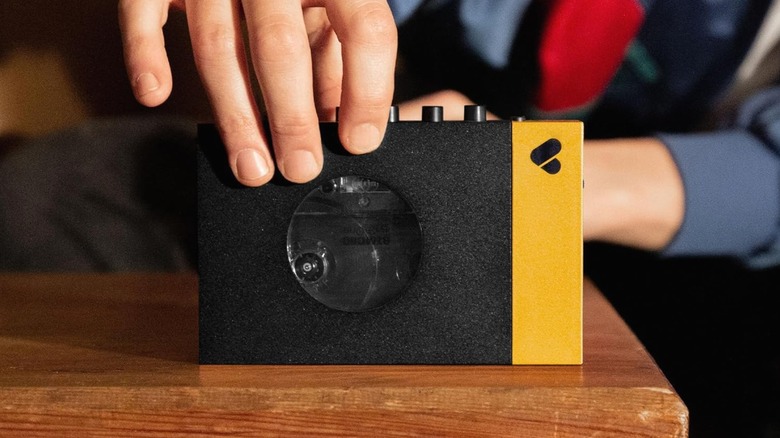 Hand holding a We Are Rewind Cassette Player on a wood table