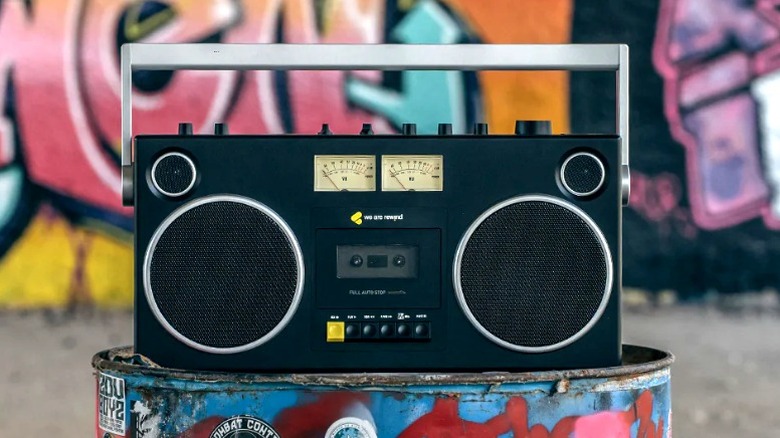 We Are Rewind Blaster GB-001 on a graffiti-covered metal barrel in front of a graffiti-covered wall