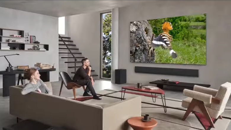 A setup of a living room with a couple watching LG OLED TV