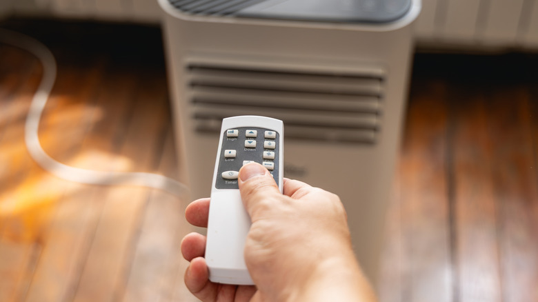 A person using a portable air conditioner remote.
