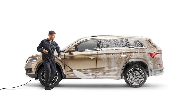 A professional detailer, detailing a car with a power sprayer