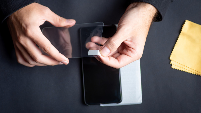 A person peeling off the plastic layer of a screen protector before applying it