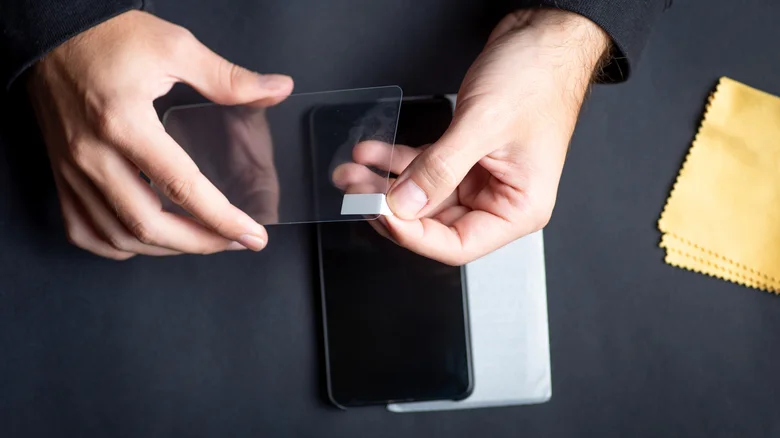 A person peeling off the plastic layer of a screen protector before applying it