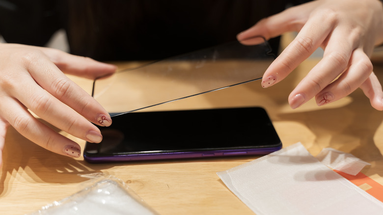A person applying a screen protector on an Android phone