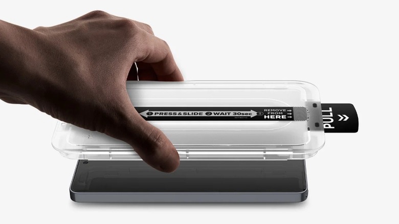 A person applying a Spigen screen protector on a smartphone