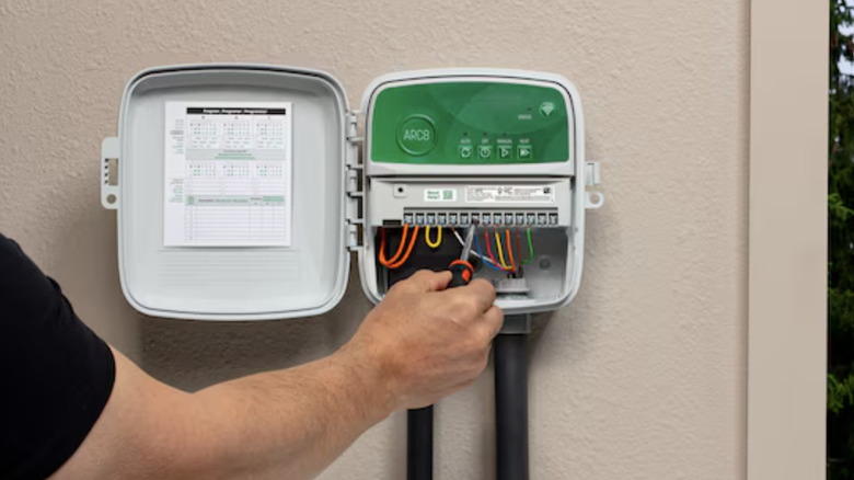 man installing Rain Bird sprinkler timer on exterior wall