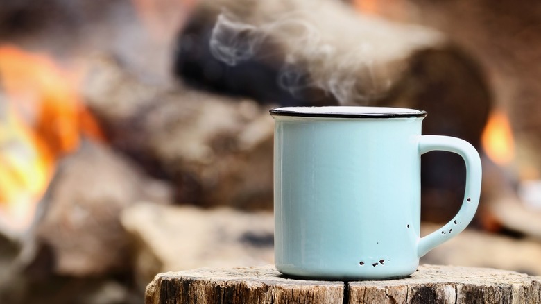 Coffee mug sitting on log
