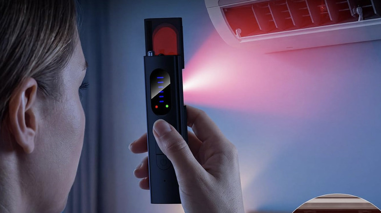 A woman holding the Nilcozy anti spy detector to detect a hidden camera in an air conditioning unit