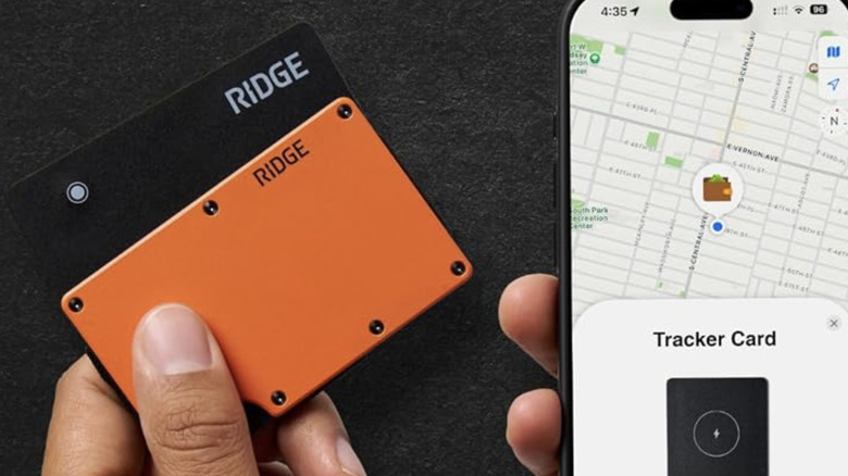 Close-up of a hand holding two Ridge Tracker Cards next to a smart phone with a tracker app open