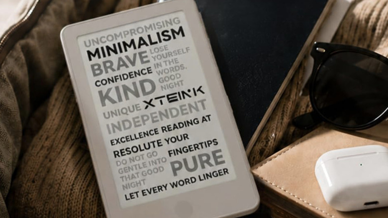 The XTEINK X4 Pro e-reader sitting on a soft surface near an AirPod case and a pair of sunglasses